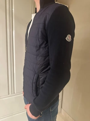 Marinblå Moncler cardigan - Hej! Säljer nu min moncler cardigan som börjar sitta lite för litet. Den är håller värmen bra och är perfekt nu inför våren, den har en bra och tight passform runt armarna och midjan. Jag på bilden är 184 och väger 73kg. Bara att höra av er vid minsta funderingar eller frågor. Priset är ej hugget i sten. 🤩😄