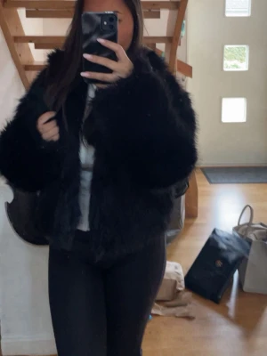 Svart fluffig pälsjacka - Säljer en svart, kort och fluffig pälsjacka med lång ärm från Gina Tricot. 
