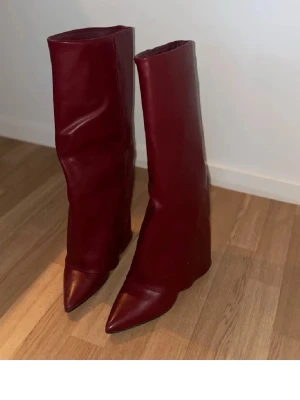 Vinröda höga stövlar i skinn - Säljer ett par vinröda höga stövlar med spetsig tå. Köpt på plick , strl 38,5