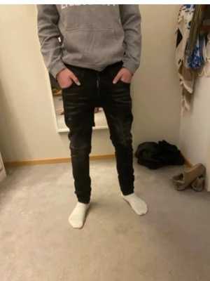 Svarta slim fit jeans från Dsquared2 - Säljer ett par svarta slim fit jeans från Dsquared2 med slitningar och tvättade detaljer. Jeansen har klassisk femficksmodell, låg midja och Dsquared2-logga bak på linningen. Perfekta för dig som gillar en trendig och avslappnad stil.