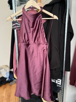 Halter neck klänning  - Vinröd halterneck-klänning i satinlook från Zara, storlek XS. Helt ny utan prislapp, feminin passform med fin glans – perfekt till fest eller middag. 