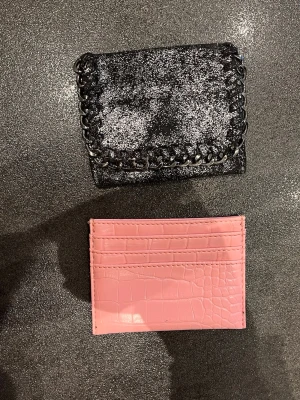 Glittrig svart plånbok & rosa korthållare - Säljer en glittrig svart plånbok med kedjedetaljer och en rosa korthållare i croc-mönstrat konstläder. 1 för 30kr och båda för 60kr