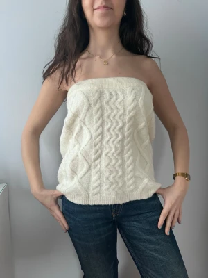 Vit stickad tubtopp - En vit stickad tubtopp med snyggt mönster. Den är väldigt skön och fungerar både som en topp eller kjol. Aldrig använd💕