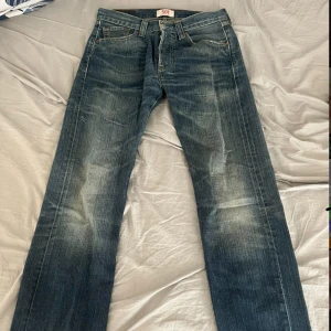 Levi's 501 blå jeans, W29 L32 - Klassiska Levi's 501 jeans i blå tvätt med snyggt slitna detaljer. Rak passform och femficksmodell, tillverkade i robust denim. Perfekta för dig som gillar en tidlös och avslappnad look.