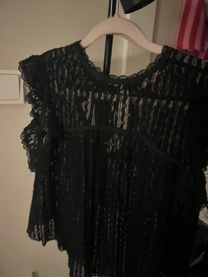 Svart spetstopp med volang - As snygg svart spets topp från Nelly, har används bara 1 gång men ingen anledning varför egentligen. Ingen effekt på användning alls, passar till fester middagar eller när man vill va lite extra