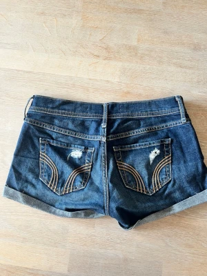 Mörkblå jeansshorts med hål - Snygga mörkblå jeansshorts från Hollister med uppvikta kanter och slitna detaljer både fram och på baksidan. 