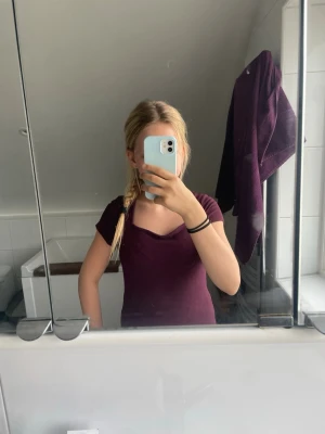 Mörklila t-shirt med v-ringning - En enkel och stilren mörklila t-shirt med v-ringad hals. T-shirten har korta ärmar och en figurnära passform som passar perfekt till jeans eller kjol. Skön och mjuk känsla, perfekt för dig som gillar en clean look.💕 