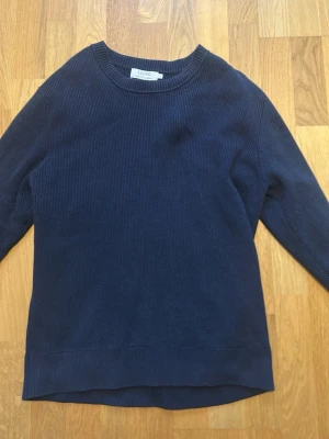 Mörkblå stickad tröja från Ljung - Mörkblå stickad tröja från Ljung by Marcus Larsson. Tröjan har rund halsringning, ribbstickad struktur och långa ärmar. Perfekt för dig som gillar enkel och stilren design. Materialet känns mjukt och bekvämt mot huden.