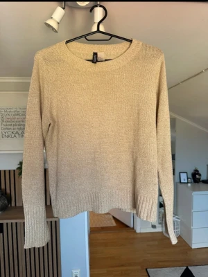 Beige stickad tröja från Divided - Stickad tröja i beige från Divided med rund halsringning och långa ärmar. Tröjan har ribbstickade muddar vid ärmslut och nederkant. Perfekt basplagg i mjukt material som passar till allt.