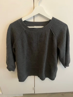 Mörkgrå stickad tröja från ASOS - Mörkgrå stickad tröja från ASOS med rund halsringning och ribbade muddar. Tröjan har en enkel och stilren design med långa ärmar och mjukt material som passar perfekt till kyligare dagar.