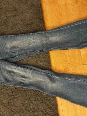 low waist bootcut jeans från vero moda - Snygga blå slim fit jeans med slitningar och ljus tvätt. Klassisk femficksmodell med dragkedja och dubbla knappar i midjan. Perfekta till en avslappnad stil och passar till det mesta.