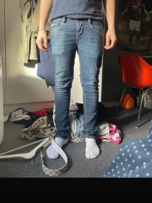 Replay jeans anbass - Säljer ett par blå slim jeans med snygga kontrastsömmar och klassiska fickor både fram och bak. Jeansen har en normal passform och är tillverkade i bomull med lite stretch för extra komfort. Perfekta för dig som gillar en stilren och enkel look.