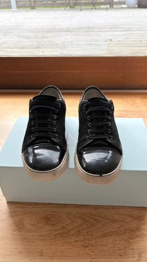 Lanvin sneakers -  Snygga svarta sneakers Från Lanvin Paris perfekt till sommaren om du letar efter ett par stiliga svarta sneakers. Har haft dem ett tag och är lite trasiga på sulan men funkar bra att ha på sig året runt.