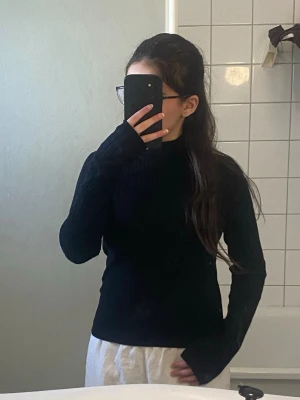 Svart stickad polotröja - Snygg svart stickad polotröja med lång ärm och ribbade detaljer vid halsen. Super snygg och skön, var skeptisk över ifall jag borde lägga ut den, men märkte att jag hade en till.