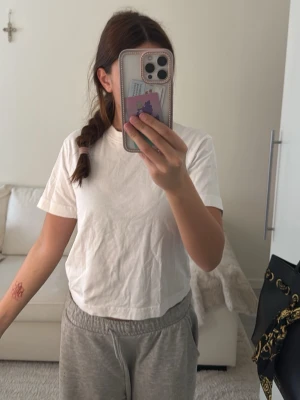 Vit basic t-shirt i bomull - Enkel vit t-shirt med rund hals och korta ärmar. Modellen är rak och något boxig, perfekt för en avslappnad stil. Tillverkad i mjuk bomull som känns skön mot huden.