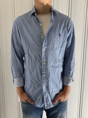 Randig skjorta från Polo Ralph Lauren - Riktigt fräsch skjorta från Polo Ralph Lauren i storlek M Slim Fit. Tröjan är blå-vit randig och är i toppenskick utan skavanker! 🤩 Ett måste inför sommaren! | Nypris: ca 1600kr | Om du har frågor eller funderingar så tveka inte på att höra av dig!🙌Priset är inte hugget i sten vid snabb affär! 🪨  