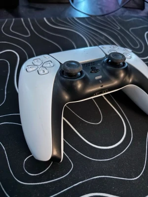 Ps5 kontroll med stickdrift - Säljer en PlayStation 5 DualSense handkontroll i svart och vitt. Den har en modern, ergonomisk design med touchpad, adaptiva triggers och inbyggd mikrofon. Tillverkad i plast och passar perfekt för gaming på PS5.