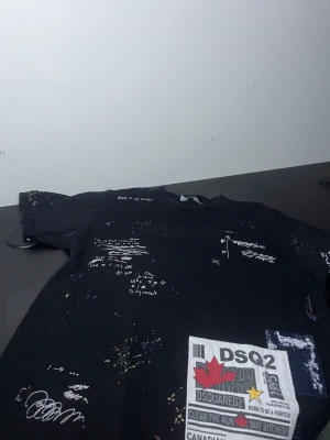 Dsquared2 tröja. - Snygg och trendig svart tröja med unika grafiska detaljer och färgstänk som ger en modern och edgy look. Perfekt för dig som vill sticka ut och samtidigt hålla en stilren bas i din outfit. Tröjan har ett coolt tryck framtill och passar lika bra till jeans som till mer uppklädda streetwear-stilar.  Storlek: S Skick: Bra skick  En riktigt stilren piece som lyfter vilken outfit som helst! ✨