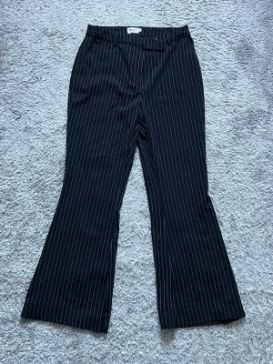 Svarta kostymbyxor NA-KD - Byxorna har utsvängda ben och klassisk passform med hällor i midjan. I superfint skick.