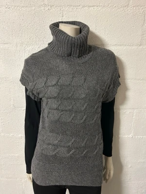 Grå stickad polotröja med kort ärm - Snygg grå stickad polotröja med korta ärmar och bred polokrage. Tröjan har ett tydligt kabelstickat mönster framtill och ribbade kanter. Perfekt att bära över en långärmad topp för en lager-på-lager-look. Helt ny från Soulmate. Ordpris 699kr.