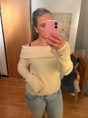 Off shoulder beige stickad tröja - Trendig off shoulder stickad tröja i beige med bred krage och ribbad struktur. Långa ärmar och mjukt material som ger en avslappnad men snygg look. Perfekt att styla med jeans eller kjol för en cool vardagsoutfit. 