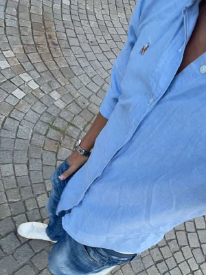 Blå Polo Ralph Lauren skjorta - Snygg ljusblå skjorta från Polo Ralph Lauren med klassisk button-down krage och broderad logga på bröstet. Skjortan har långa ärmar och knäppning framtill. Perfekt för en clean och stilren look. Skriv vid frågor eller funderingar!😊