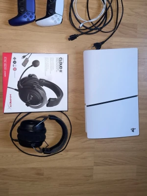 PS5 Slim + 2 kontroller + HyperX Cloud II + tillbehör – Komplett paket - Säljer en PlayStation 5 Slim i fint skick tillsammans med tillbehör – redo att spela direkt.  Detta ingår: • PS5 Slim (fullt fungerande) • 2 DualSense-kontroller (vit + blå) • HyperX Cloud II gaming headset (med originalkartong) • Extra öronkuddar till headsetet • Mikrofon + kontrollenhet (7.1-ljud) • HDMI-kabel, strömkabel och laddkabel  Skick: Allt fungerar som det ska. PS5:an har några mindre repor på ovansidan (endast kosmetiskt, påverkar inte funktion). I övrigt är allt i mycket bra skick. 