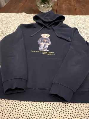 Hoodie Polo Ralph Lauren Polo Bear 🐻 - Navy blue hoodie featuring the iconic Polo Bear by Ralph Lauren. Appears in excellent condition with no visible flaws.  feels like L but the shirt says XL you know how it is with Ralph Lauren   ⭐️ Condition: 9/10 🎲 Size: XL 🎨 Color: Navy Blue 📦 Fast and careful shipping