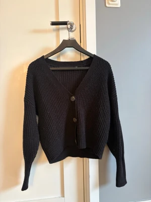Svart stickad kofta med knappar - Snygg svart stickad kofta med v-ringning och tre knappar framtill. 