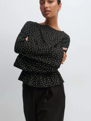 Svart prickig blus med volang - Trendig svart blus med vita prickar och volang nedtill. Långärmad modell med lätt utsvängda ärmar och smockad midja som ger en snygg siluett. Perfekt att styla med både jeans och kostymbyxor. Från gina, använd fåtal ggr!