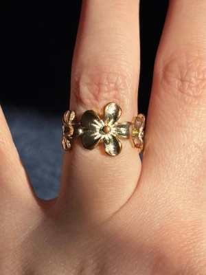 Guldfärgad Ring med Blomster Motiv - I fint använt skick. Lite missfärgad eftersom den använts en del. Storlek är cirka 16 mm i diameter.