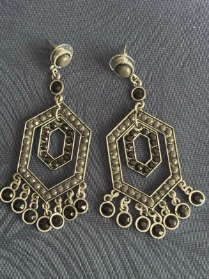 Tunga Geometriska Silverfärgade Örhängen i metall - Unika örhängen i silverfärg med geometrisk hexagonform och svarta stenar. Hängande design med flera små cirklar längst ner som ger extra rörelse. Perfekta för dig som gillar statement-smycken med coola detaljer. I jättefint skick. Ingen stämpel.