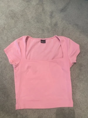 Rosa topp med fyrkantig urringning - Söt rosa topp från Gina tricot med korta ärmar och en snygg fyrkantig urringning. Tillverkad i mjuk bomull som känns skön mot huden. Perfekt att styla med jeans eller kjol för en trendig look.