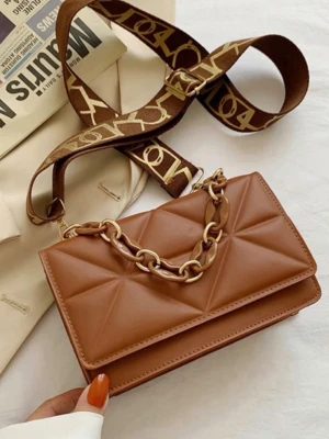 Brun quiltad handväska med kedja - Snygg brun handväska i quiltad design med guldfärgad kedjedetalj och bred axelrem med mönster. Väskan har en rektangulär form och är tillverkad i konstläder. Perfekt accessoar för att lyfta din outfit.