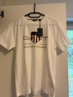 Vit GANT t-shirt med logga - Snygg vit t-shirt från GANT med klassisk Archive Shield-logga. Aldrig använd. Storlek 170/XS
