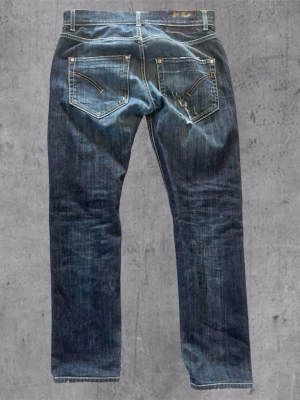 Mörkblå jeans med slitningar - Snygga mörkblå jeans med raka ben och slitna detaljer på framsidan. Klassisk femficksmodell med kontrastsömmar och dragkedjor på bakfickorna. Perfekta för en avslappnad streetstil.