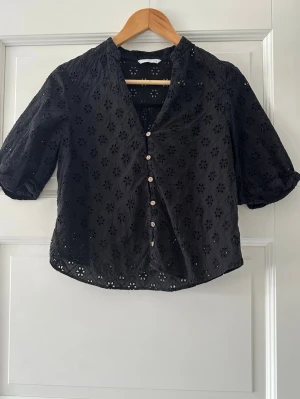 Svart blus  - Svart blus med v-ringning och knappar framtill. Tillverkad i ett lätt och luftigt material som ger en avslappnad men ändå stilren look.
