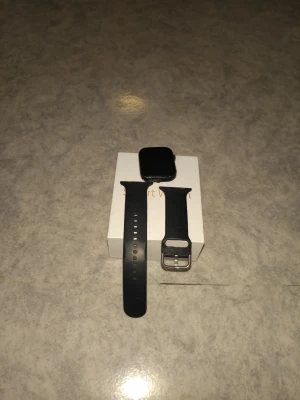Svart smartklocka med silikonarmband - Snygg svart smartklocka med fyrkantig display och utbytbart svart silikonarmband. Klockan har en modern look och passar perfekt till dig som gillar teknik och vill ha koll på notiser och hälsa direkt på handleden. Levereras med originalförpackning.