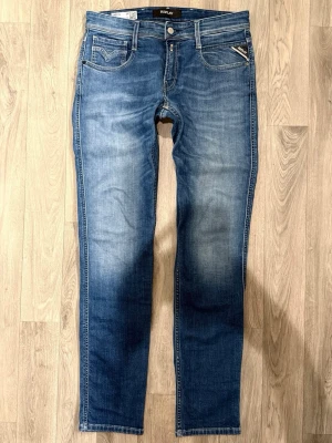 Replay Anbass Jeans Blå W29/L32 - Slim Fit - Replay Anbass blå jeans med slim fit passform som sitter snyggt och bekvämt och funkar till allt, storlek W29/L32, midja 40 cm, ytterbenslängd 104 cm, benöppning 16 cm, modellen är 185cm & väger 65kg, i fint skick.