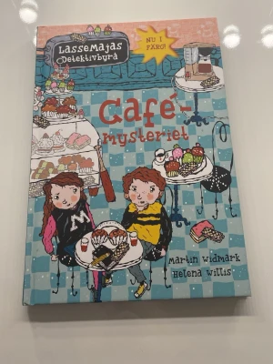 Cafémysteriet - LasseMajas Detektivbyrå - Säljer boken 'Cafémysteriet' från LasseMajas Detektivbyrå, skriven av Martin Widmark och illustrerad av Helena Willis. Perfekt för dig som gillar mysterier och spännande berättelser.