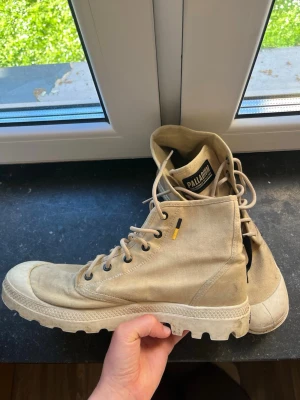 Palladium boots - Supersköna Palladium boots i sandfärg. Bootsen är använda och har tecken på användning såsom de fläckar som kommit främst vid hälarna. Förutom de fläckar som uppkommit är skorna i gott skick. De har även vaxats och har därför en viss vattentäthet. 