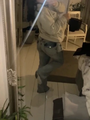 Utsvängda Ljusblåa jeans med låg midja - Säljer ett par ljusblå jeans med låg midja och utsvängda ben, med snygga knappar där bak på fickorna, byxorna har små fläckar på benen som knappt syns men går säkert bort i tvätten, byxorna är använda men har inga skador och är köpta för inte så länge sedan. 
