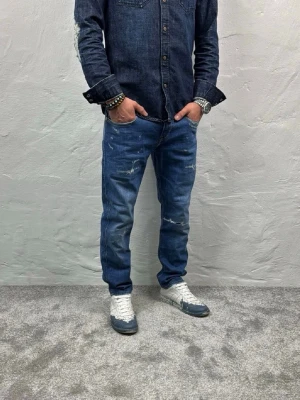 Blå Replay jeans med slitningar  - Snygga blå Replay med slitna detaljer och lätt tvättad look, i storleken W 30, L 30. Jeansen har klassisk femficksdesign och normal midja. Perfekta för en avslappnad och trendig stil. Hör av dig vid minsta lilla fundering