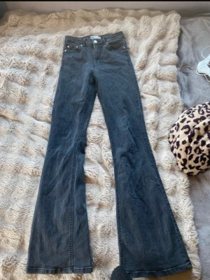 Svarta bootcut jeans med hög midja - Säljer ett par svarta bootcut jeans med hög midja och klassisk femficksdesign. Jeansen har vida ben och stängs med knapp och dragkedja. Perfekta för dig som gillar en retro och avslappnad stil.