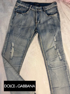 Ljusblå slitna jeans från Dolce & Gabbana - Snygga ljusblå jeans från Dolce & Gabbana med slitna detaljer och klassisk femficksmodell. Jeansen har en slim fit-passform och är tillverkade i mjuk denim med stretch. 