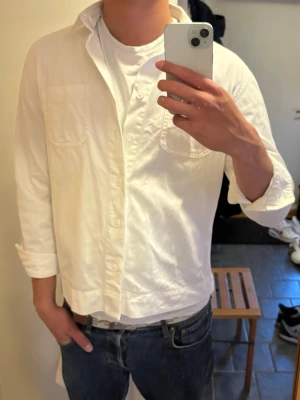 Vit overshirt från No  - Säljer en vit overshirt från No i storlek L. Skjortan har två bröstfickor, knappar framtill och är gjord i mjuk bomull. Perfekt för en clean och avslappnad stil. (Skulle säga att storleken är mer M)