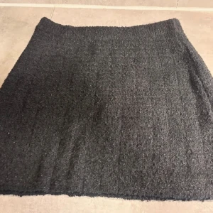 Svart stickad kortkjol - Säljer en enkel och stilren svart stickad kortkjol. Kjolen har en rak passform och är gjord i ett mjukt, värmande material som passar perfekt till kyligare dagar. Stretchig kvalitet.