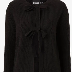 Svart stickad kofta med knyt - Trendig svart stickad kofta med croppad passform och långa ärmar. Koftan har snygga knytband framtill och baktill som ger en öppen känsla både fram och bak. Perfekt för dig som vill ha en unik och stilren look. 