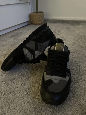 Valentino Rockrunner camo sneakers - Säljer ett par Valentino Rockrunner sneakers i svart, grått och vitt med camouflagemönster. Köpte för nypris, använda ett antal gånger därav det billiga priset. Dustbags ingår givetvis.