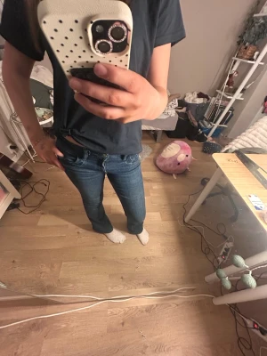 Mörkblå bootcut jeans - Säljer ett par mörkblå bootcut jeans med klassisk femficksdesign och låg midja. Jeansen har en snygg tvätt och sitter tajt över låren för att sedan bli vidare nedtill. Perfekta till vardagslooken och passar till det mesta.